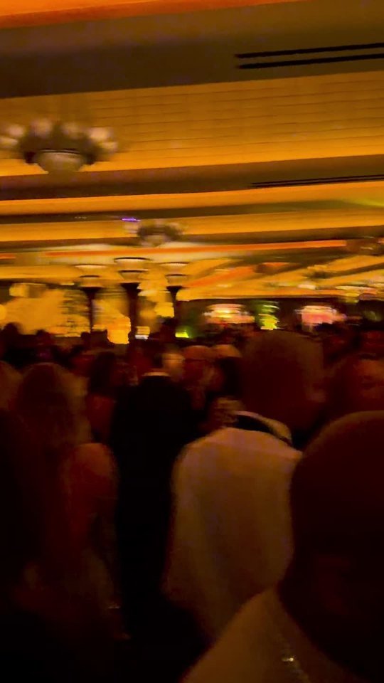 The gold-lit room and opening-night gathering. Video still.