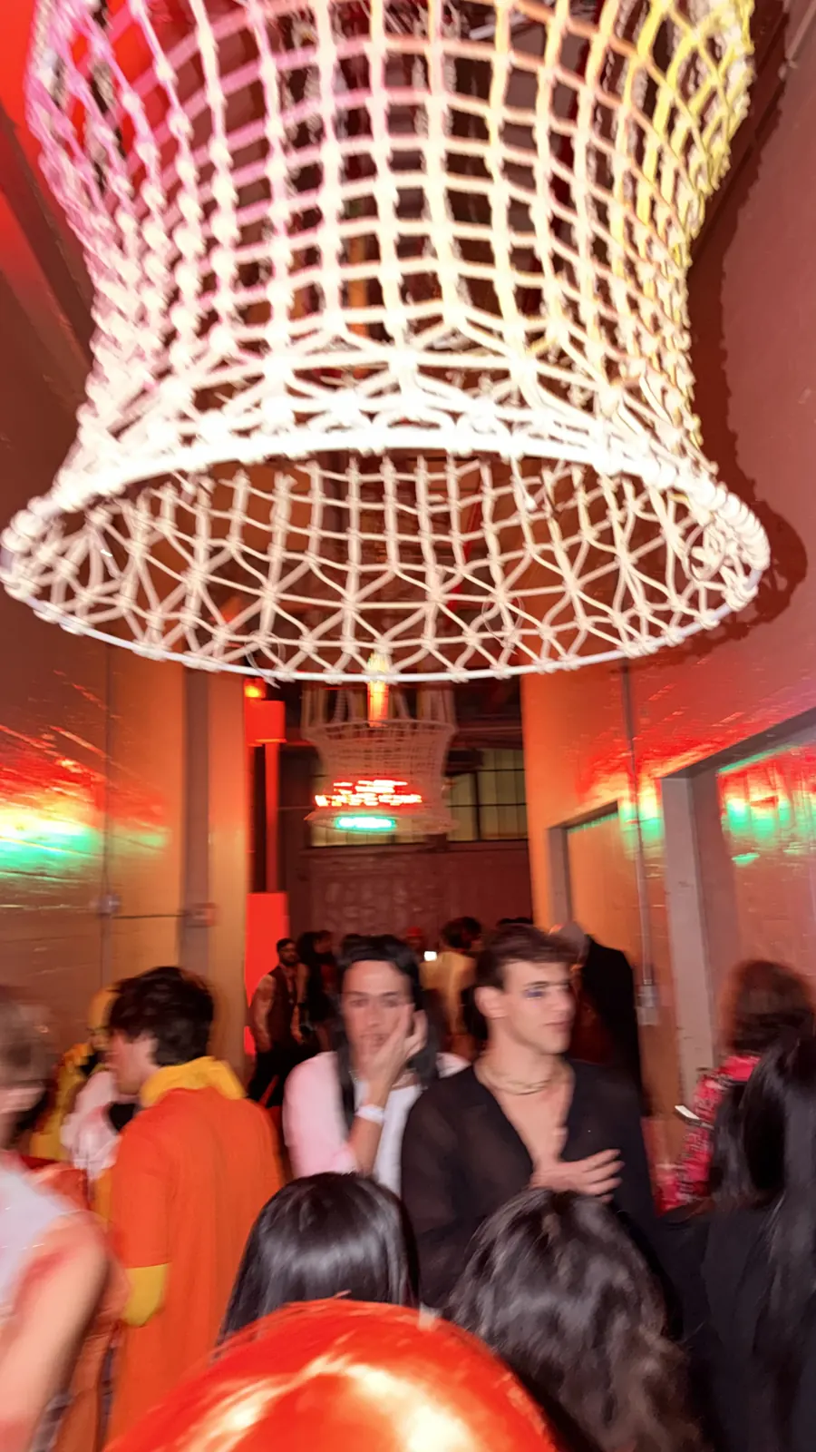 A sculptural light hangs above costumed guests inside Industry City.