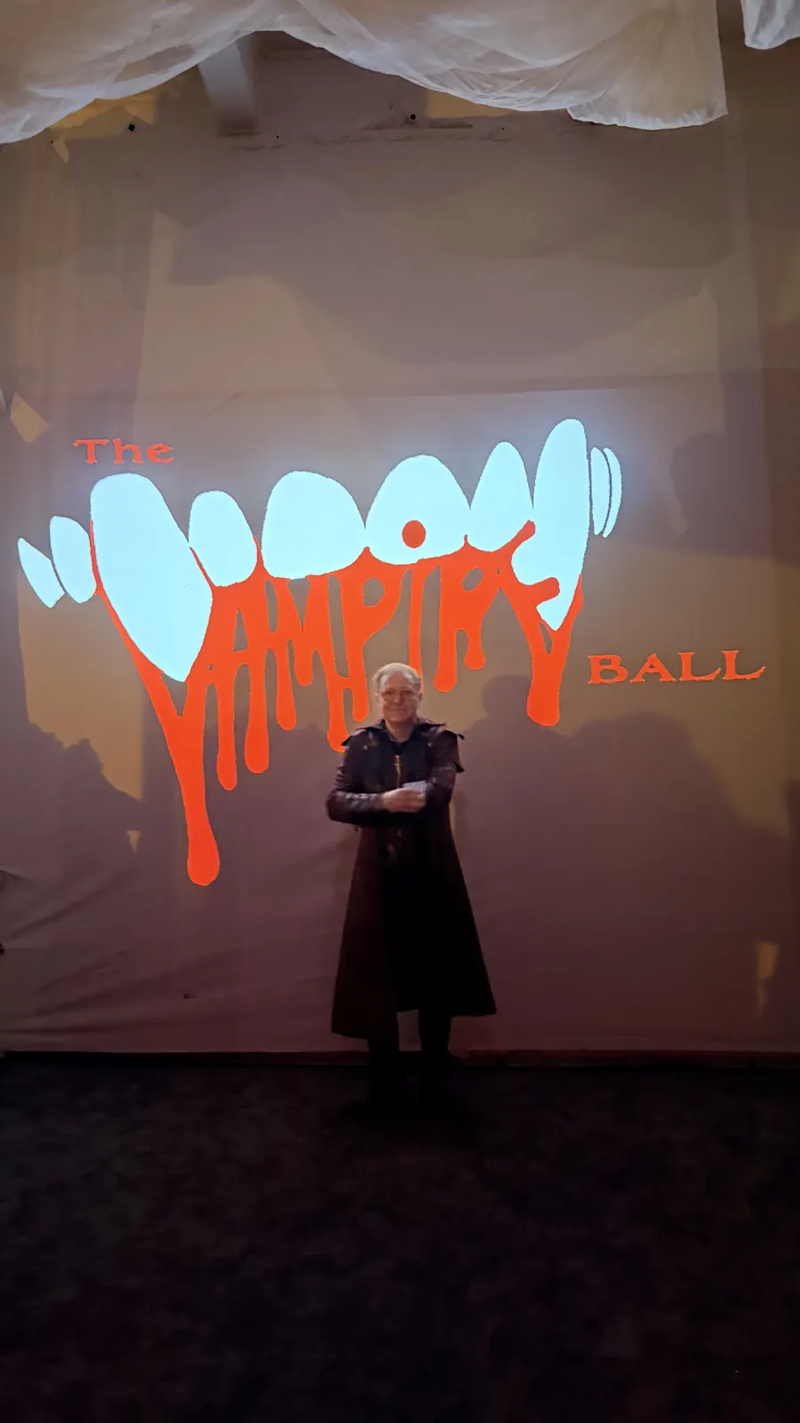 A guest poses in front of the Vampire Ball projection.